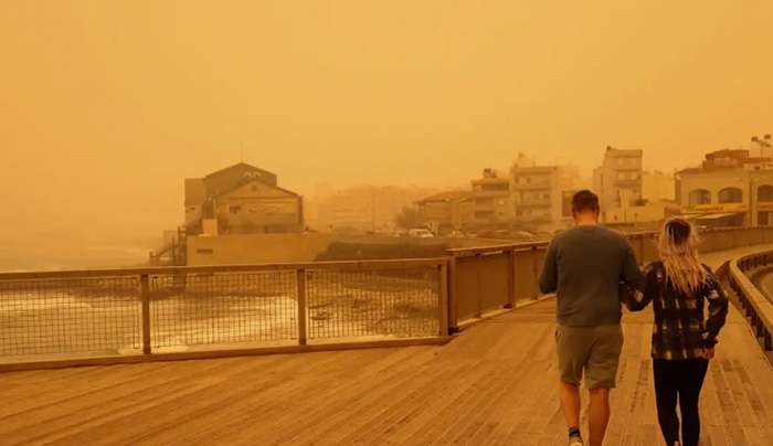 People walk in a haze, caused by sand dust from the Sahara, due to strong southern winds, in Heraklion, Crete island, Greece, April 1, 2026. REUTERS/Stefanos Rapanis